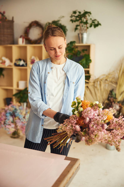 Focused fiorista professionista ammirando un bouquet nelle sue mani - Foto, immagini