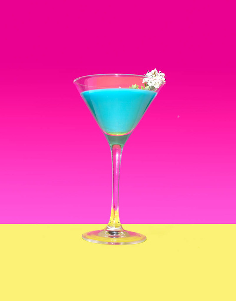 Un cocktail bleu moderne avec une fleur blanche avec un fond magenta lumineux et un fond jaune chaud. Un seul et unique concept optimiste maître. - Photo, image