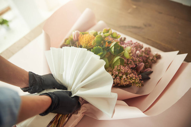 Kobieta w rękawiczkach nitrylowych owijając bukiet kwiatów mieszanych - Zdjęcie, obraz