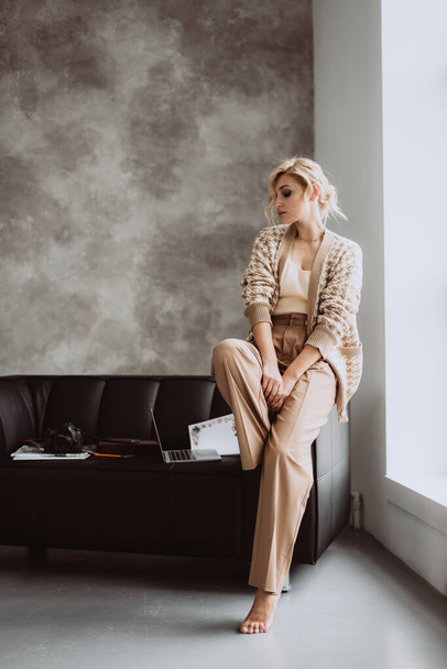 Young beautiful woman blogger in a modern loft interior. Woman photographer freelancer in beige stylish clothes. Soft selective focus. - Foto, immagini