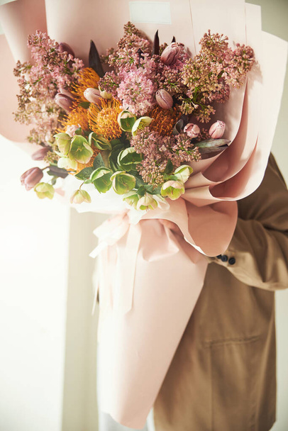 Чоловік тримає прекрасну завершену квіткову композицію в руці
 - Фото, зображення