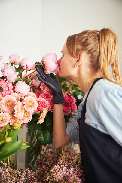 Floral designer smelling the aroma of a fresh-cut flower - Photo, Image