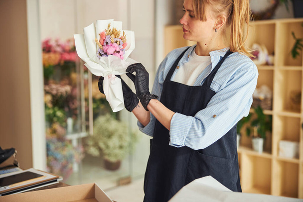 Fleuriste expérimentée concentrée examinant un arrangement floral dans ses mains - Photo, image