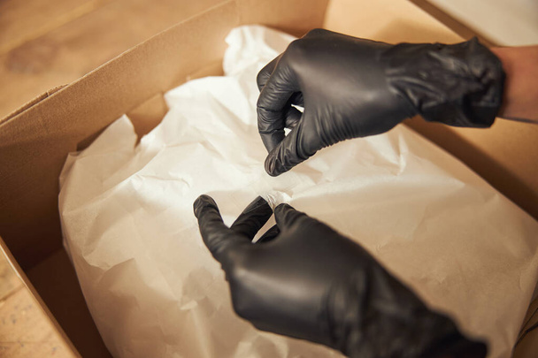 Pracownik w rękawiczkach nitrylowych przygotowujący opakowanie do wysyłki - Zdjęcie, obraz