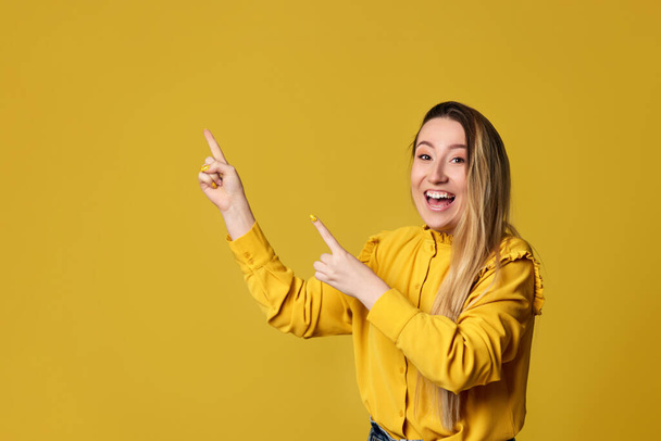 young woman pointing away on yellow background - Foto, immagini