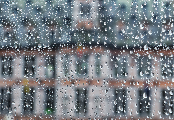 Gebäude sichtbar durch Glas, das von Regentropfen bedeckt ist - Foto, Bild