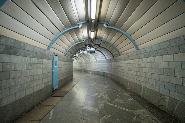 Tunel pustego futurystycznego przejścia podziemnego o gładkim zakręcie, wyłożony marmurowymi płytkami. - Zdjęcie, obraz