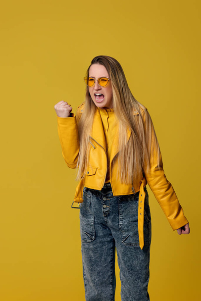 angry woman in sunglasses screaming on yellow background. - Foto, afbeelding