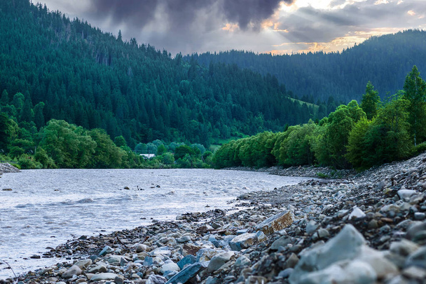 Río claro con rocas conduce hacia las montañas iluminadas por el atardecer - Foto, imagen