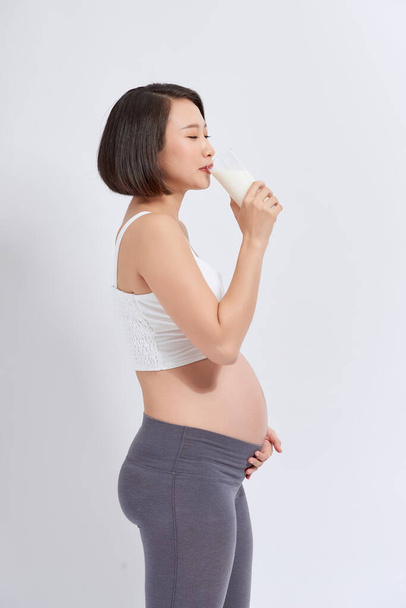 Pregnant woman holding glass of milk in her hand good healty, isolated on white background. - Photo, Image