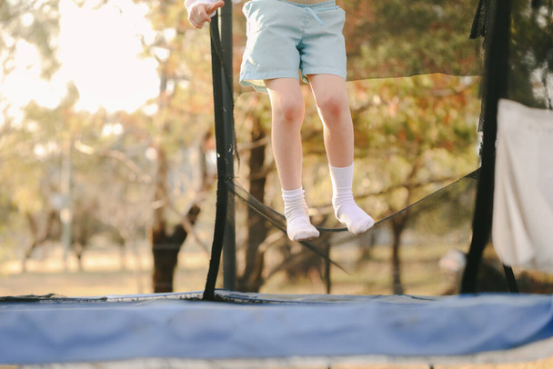 A closeup of a little boy jumping high on a trampoline; a shot without face - Foto, afbeelding