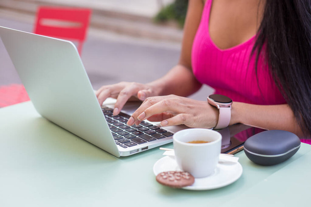 A closeup shot of a woman sitting in an outdoor cafe and working with her laptop - Foto, imagen