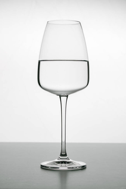 Beyaz zemin üzerinde saf suyla dolu zarif kristal bardaklar. Kırmızı ya da beyaz şarap için cam eşyalar. Barlar, restoranlar, içecekler, yaşam tarzı. - Fotoğraf, Görsel