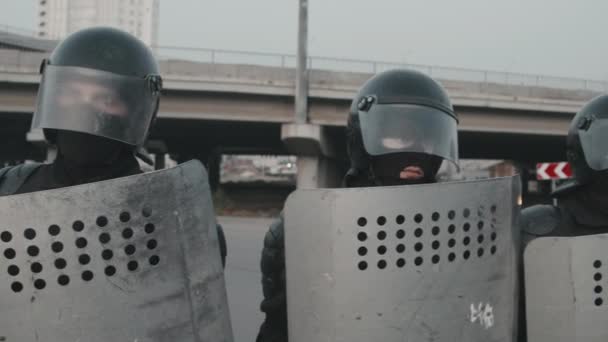 Slowmo śledzenia strzał funkcjonariuszy policji zamieszek w maskach i kaskach posiadających tarcze i blokowania ulicy podczas protestu - Materiał filmowy, wideo