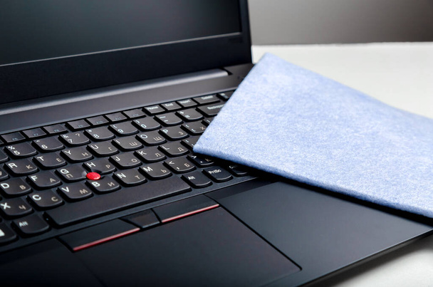 Laptop keyboard and cloth for cleaning surfaces. Disinfection new normal for cleaning workplace surfaces, office gadgets. Sanitize computer pc keyboard wiping by wet tissue. - Foto, imagen