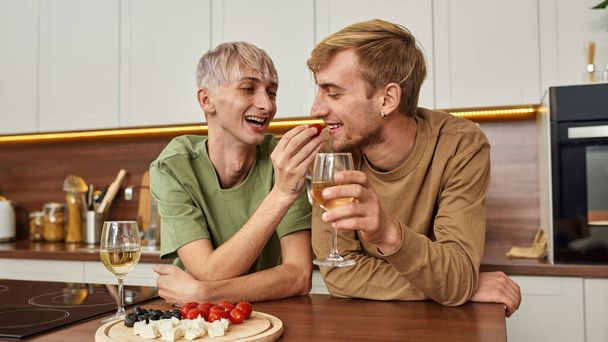 Homosexual male couple eating snacks and drinking wine - Φωτογραφία, εικόνα