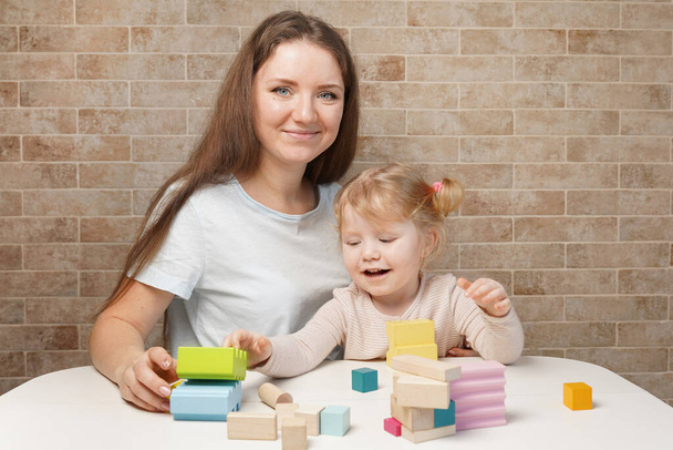 Мать с ребенком играет с деревянными блоками дома - Фото, изображение