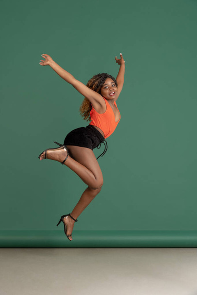 Pretty african american young woman posing on green studio background. Concept of motion, youth, human emotions, facial expression. - Foto, Imagen