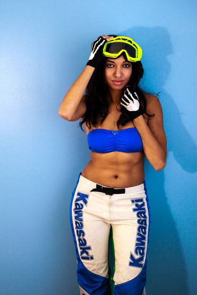 young beautiful woman in sportswear and ski goggles posing on blue background - Fotó, kép