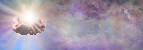 Bannière céleste de ciel de concept de force de vie - mains coupées masculines divines avec l'énergie lumineuse blanche d'or brillante émergeant du beau fond de ciel éthéré bleu rose avec l'espace de copie                            - Photo, image