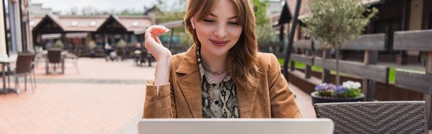 Mosolygó nő fülhallgató nézi laptop teraszán kávézó, banner  - Fotó, kép