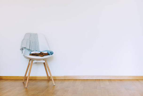 Drinnen flache Wandattrappe mit Clothes on Chair im minimalistischen Stil. Erdtöne im Hintergrund. Innenraum im luftigen, hellen Stil mit Holzboden - Foto, Bild