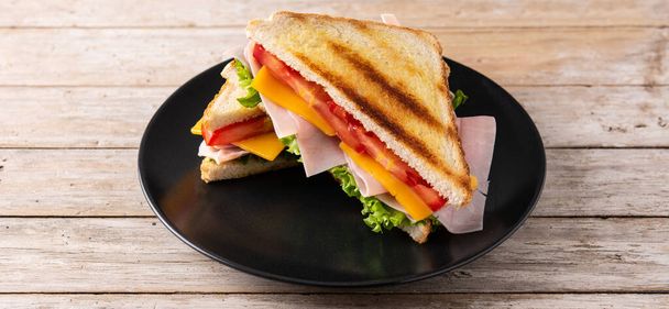 Sandwich met tomaat, sla, ham en kaas op houten tafel. Panoramisch uitzicht - Foto, afbeelding