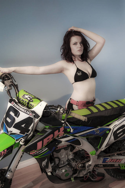 young beautiful woman in sportswear posing near motorbike - Fotó, kép