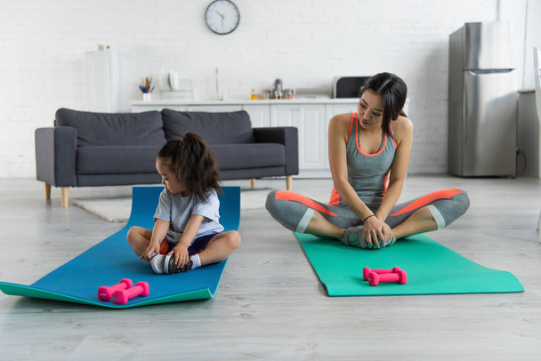 Asian mother and kid training near dumbbells at home  - Photo, Image