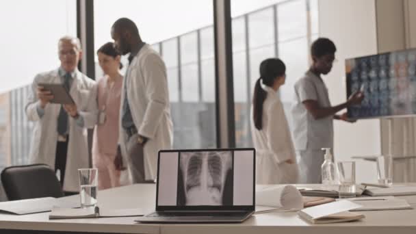 Keskipitkä hidas monikansallisten radiologien ryhmä, joka konsultoi toisiaan nykyaikaisella klinikalla rintakehän röntgenkuva kannettavan tietokoneen näytöllä valikoivasti - Materiaali, video