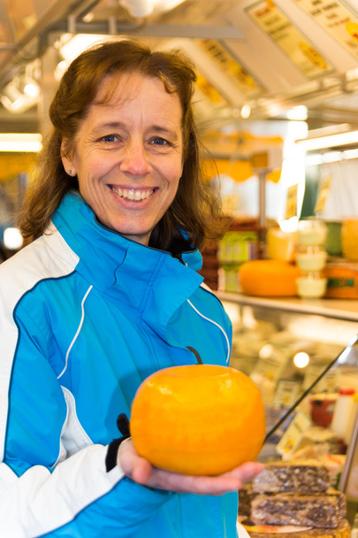 Frau zeigt runden Käse - Foto, Bild