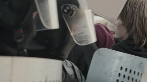 Handheld slowmo shot młodych protestujących naciskając na tarcze policji zamieszek - Materiał filmowy, wideo