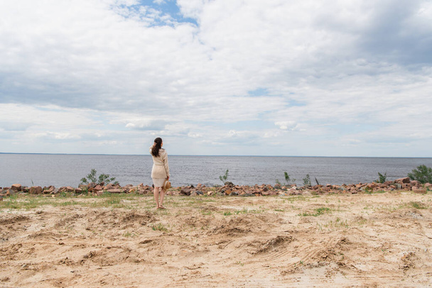 piena lunghezza di bruna giovane donna con cappello da sole e in piedi vicino al mare - Foto, immagini