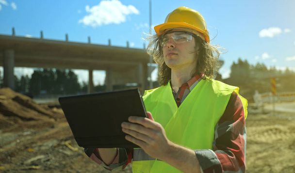 Stavitel s tabletem PC na staveništi silničního uzlu. - Fotografie, Obrázek