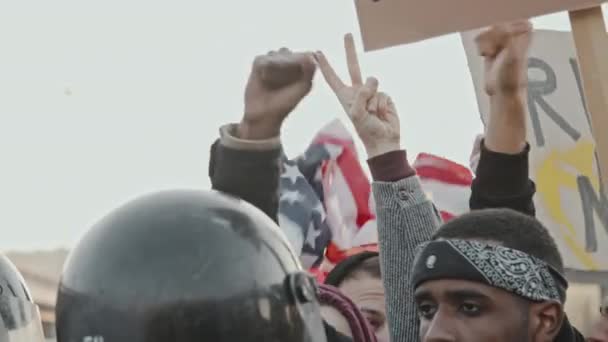 Hidas laukaus erilaisista mielenosoittajista, joilla on kyltit ja USA:n lippu laulamassa mellakkapoliiseille - Materiaali, video