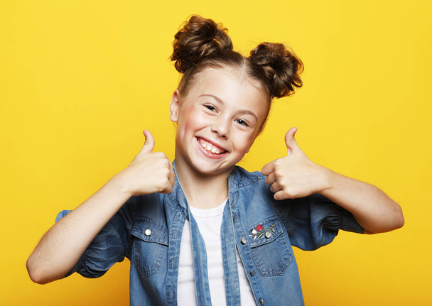 beautiful and confident girl showing thumbs up isolated over yellow background - Foto, Bild
