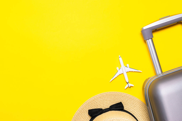 Strand achtergrond. Dames accessoires reiziger: koffer, wit vliegtuig, zonnebril op gele achtergrond met lege ruimte voor tekst. Ontwerp van zomervakantie concept - Foto, afbeelding