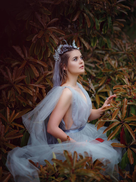 a beautiful woman like a fairy or nymph walking in the park. fairy tale image art photo. nymph of forest Near a beautiful, unusual tree - Photo, Image