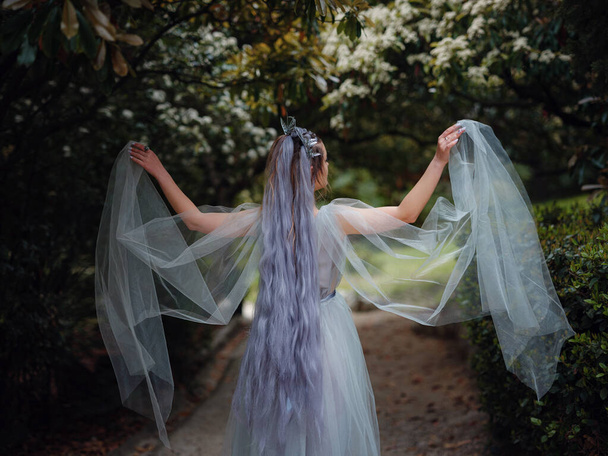 a beautiful woman like a fairy or nymph walking in the park. fairy tale image art photo. nymph of forest dancing in the dark - Photo, Image