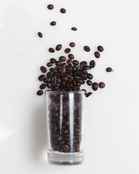 Granos de café sobre un fondo blanco brillante. Este es un grano de café árabe. El sabor distintivo del café Arabica es en forma de una consistencia ligera y un nivel de acidez más alto que otros cafés. - Foto, imagen