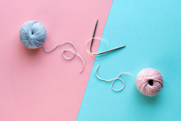 Wool yarn balls and knitting needles with string on split pink and mint blue paper background. Creative minimal simple flat lay, top view, craft concept picture. - Photo, Image