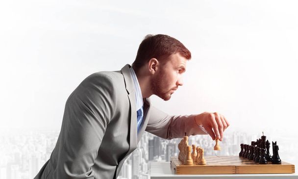 Concentrated businessman playing chess game - Photo, image