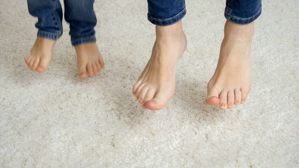 Primer plano de los pies de la madre y el niño saltando sobre una alfombra suave - Foto, Imagen