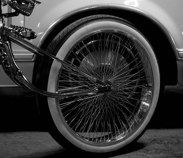 Part of a bicycle wheel with spokes on the background of car.  bike  wheel of luxury car - Fotó, kép