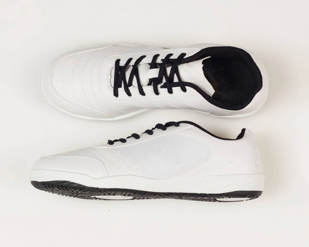 Weiße und schwarze Sportschuhe auf hellem Hintergrund. Schuhe, die beim Sport angenehm zu tragen sind. Leicht und zugleich flexibel. Freier Platz für Ihre Anzeige. Schuhattrappe. - Foto, Bild