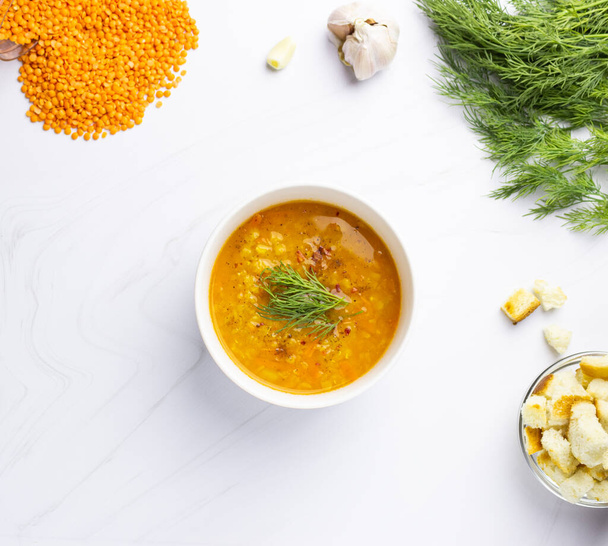 Red lentil soup with ingredients on a light background. Traditional Turkish or Arabic spicy lentil and vegetable soup, healthy vegan food. Top view. - Photo, Image