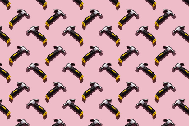 Hammers on pink background, pattern, hard shadows. Construction tools, repairs. Background for the design. - Photo, Image