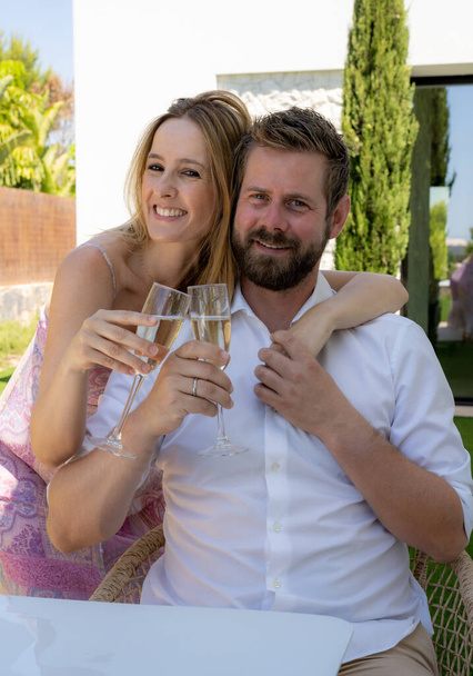 Beautiful young couple drinking champagne and smiling at home. - Photo, Image