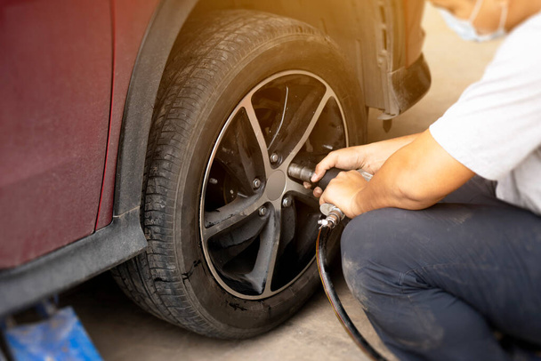 man repairs a car, putting on wheels, changing tires. Remove the wheels of the car in preparation for tire patch. car maintenance concept. - Foto, imagen