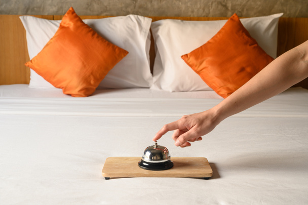 Detailní záběr ruky hosta, jak zvoní na hotelový zvon v hotelovém pokoji. Hotelový zvonek se obvykle používá k volání personálu služby a personál může pomoci hostům s jakýmikoli dotazy, které mohou mít. - Fotografie, Obrázek